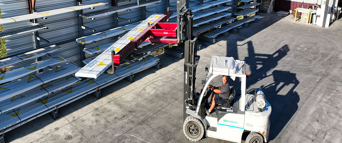 Forklift operator loading metal roof panels at their supplier warehouse, in preparation for wholesale orders from roofing contractors in Sarasota, Florida.