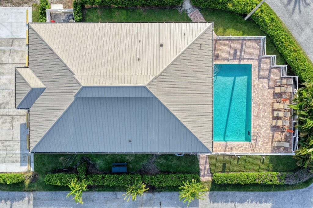 Top-down aerial drone view of a beige hip-style residential roof, illustrating clean architectural panel lines among diverse Metal Roofing Types supplied by Sunshine Metal Supply.