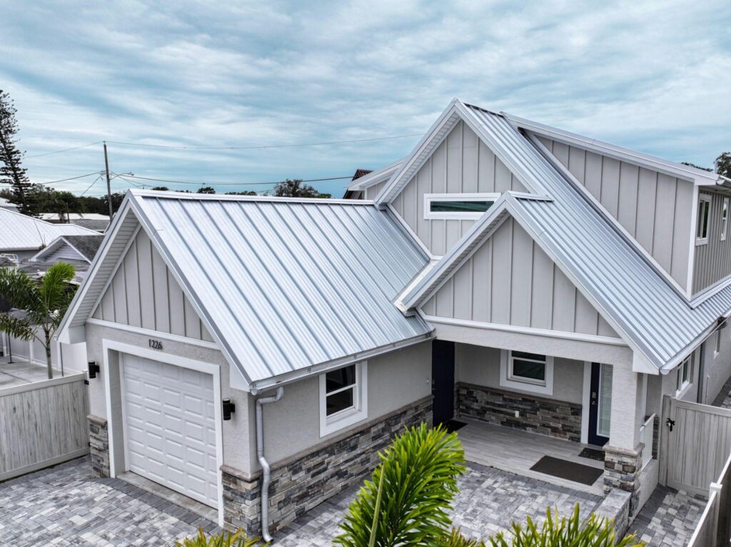 A high-angle field photo of a modern multi-gabled coastal home featuring a silver standing seam Metal Roofing Bradenton FL system supplied by Sunshine Metal Supply.