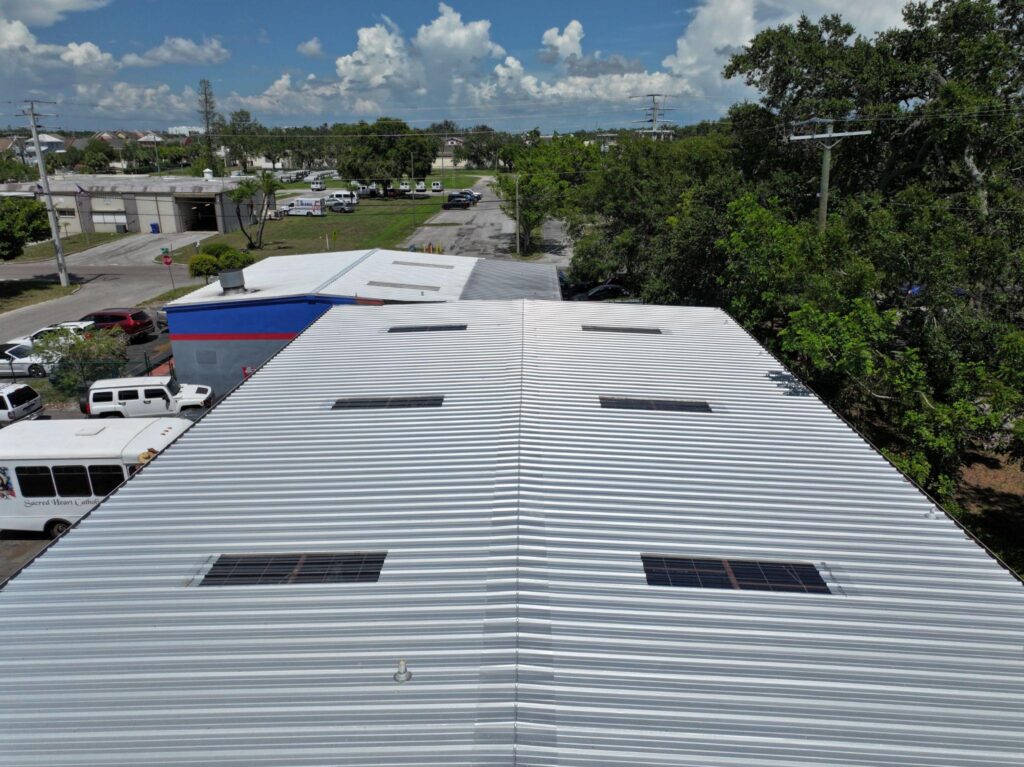 High-altitude drone perspective of a wide commercial building outfitted with a continuous corrugated system, illustrating bulk options for Metal Roofing Naples FL from Sunshine Metal Supply.