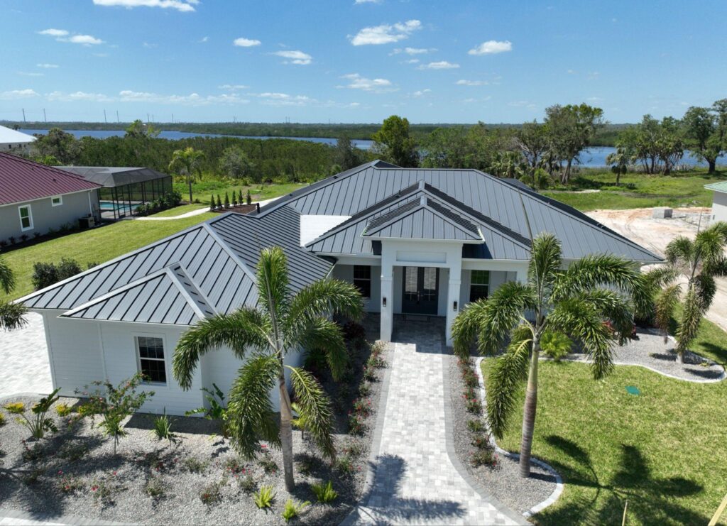 Drone photography of a luxury custom home addition with a dark gray architectural metal roof, completed with a SUNLOC Standing Seam installation by Sunshine Metal Supply.